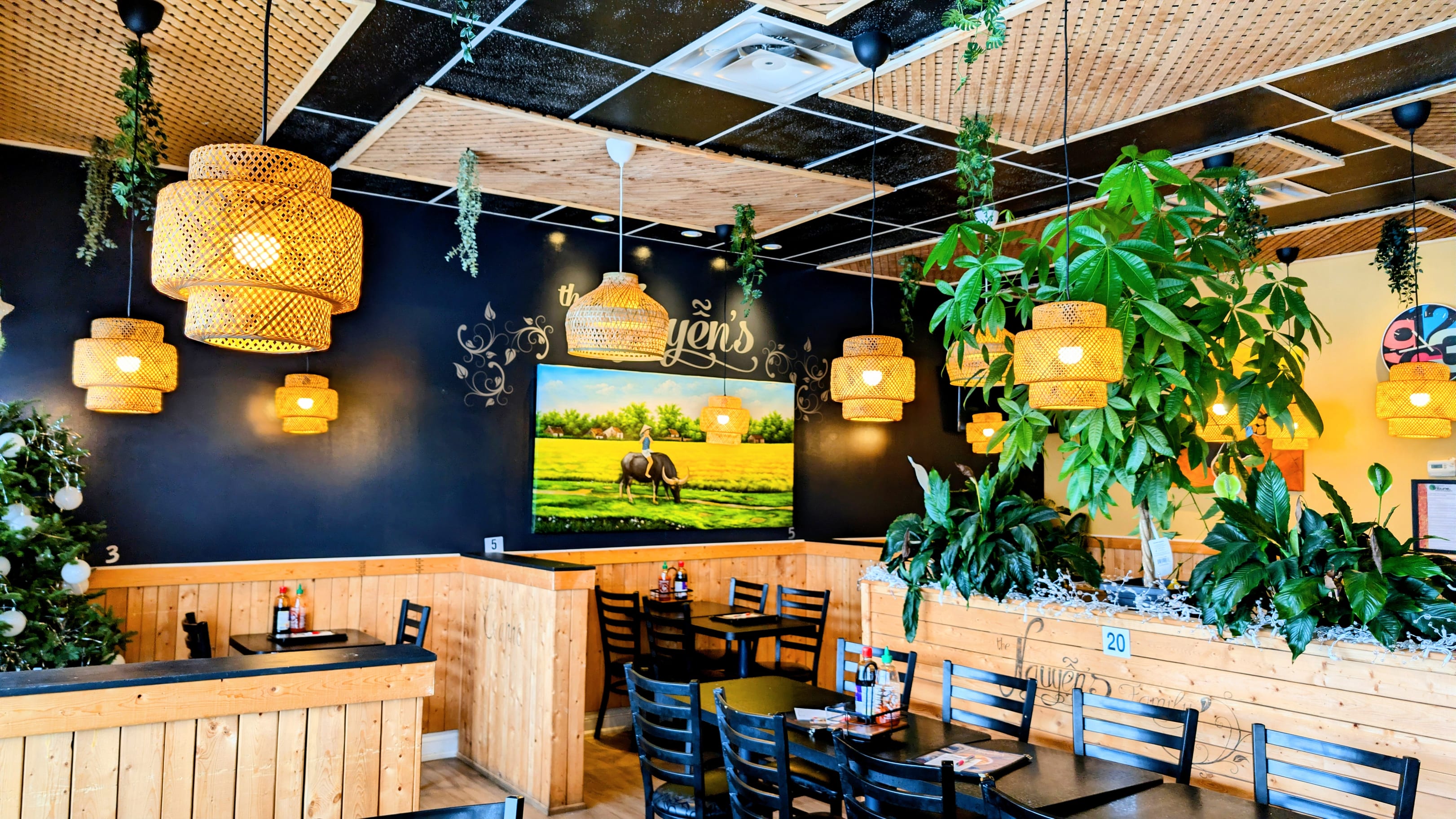 The dining room at The Nguyen's, with rattan lanterns, hanging plants and wooden booths